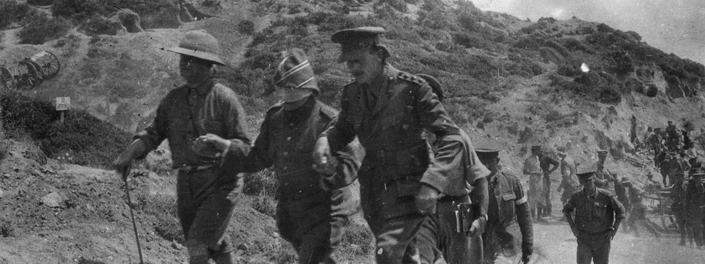 Major Kemal Ohri is led by the hand along the beach by two officers from Anzac headquarters as an envoy to negotiate an armistice to bury the dead.